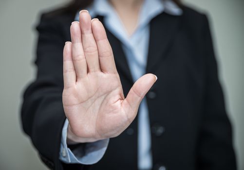 Professional woman in business suit shaking one hand and denying on grey background 