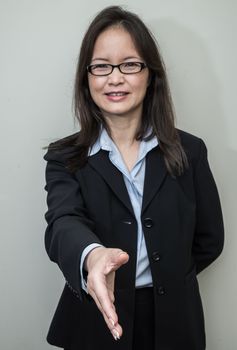 Professional woman in business suit ready for hand shake with grey background 