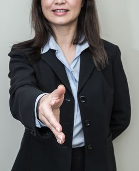 Professional woman in business suit ready for hand shake with grey background 