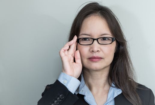 Portrait of woman with glasses in business suit smiling on grey background 