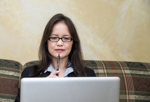 Professional woman in business suit on sofa in deep thought with laptop 