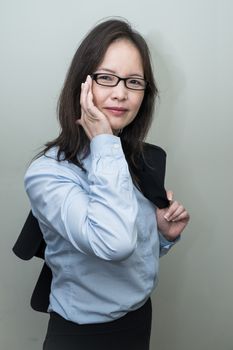 Professional woman in business casual with jacket on her shoulder on grey background