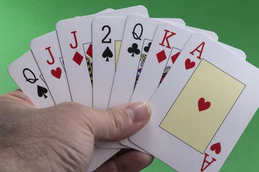 Hand holding a royal flush hearts on green