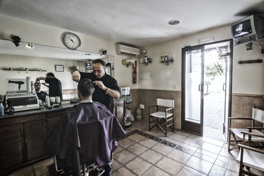 Barber shaving with a razor to young man in a barber's shop, Sabiote, Jaen province, Andalucia, Spain