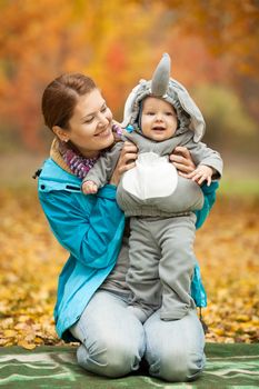 Portrait of young woman and her baby boy dressed in elephant costume in autumn park