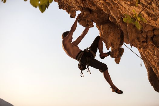 Rock climber of a cliff against sky at sunset