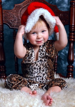 Little boy sitting on a fur dresses up santa's hat