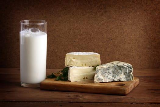 Soft cheese on wooden board and a glass of milk 