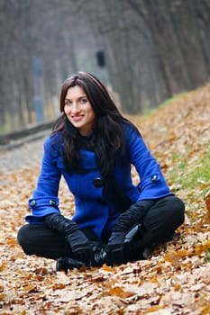 Young woman sitting in the autumn park