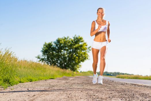 young athletic woman running on the road, exercise outdoors