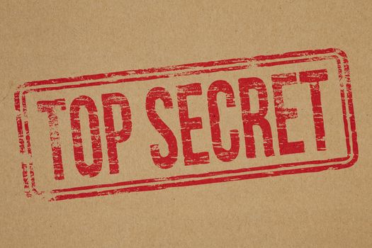 Top secret rubber stamp impression on brown paper background
