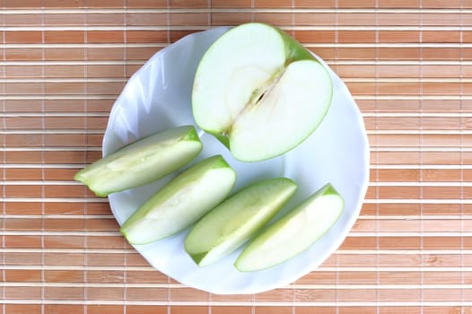 Apple with a pieces on the plate at the textured background