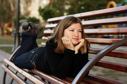 Young women lies on bench in a park