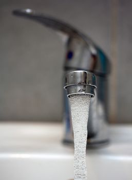 Water tap with flowing water. Selective focus, shallow depth of field