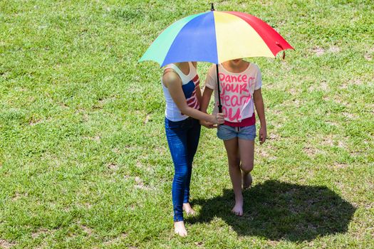 Young girls using umbrella on hot summers day for sun protection