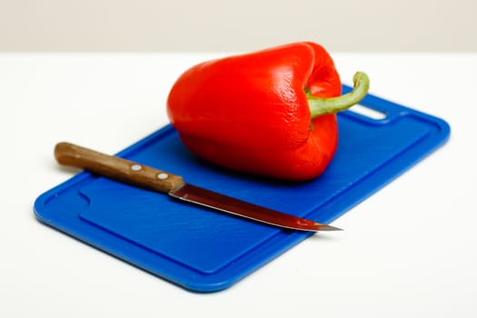 Red pepper and a knife on a cutting board