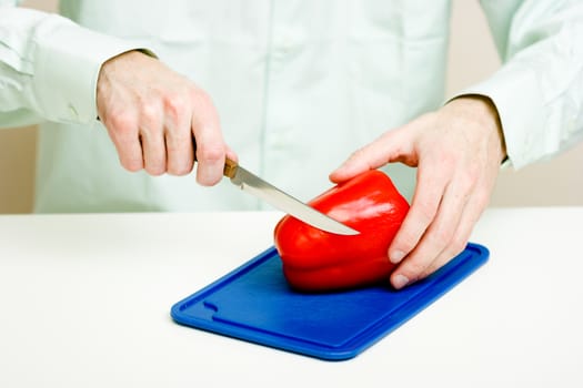Man's hand cut red pepper on a cutting board