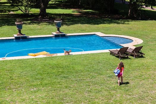 Young girl walking towards home swimming pool on a hot summers day.