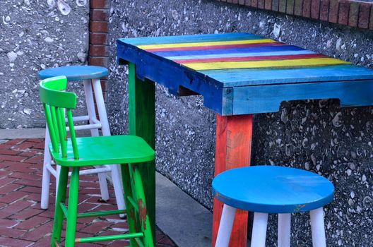 Brightly painted wooden furniture sitting on a brick and tabby patio