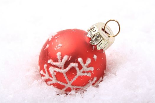 red christmas balls with white pattern on artificial snow 
