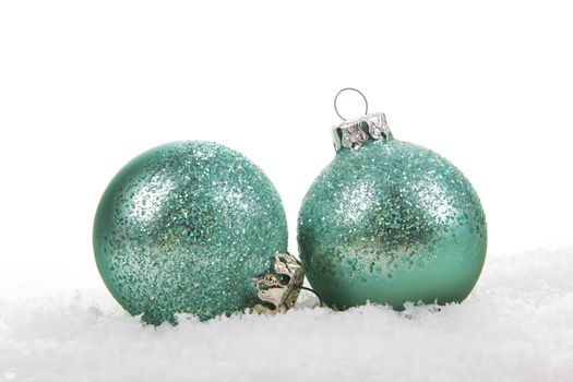 Christmas balls green, turquoise on artificial snow on white background 