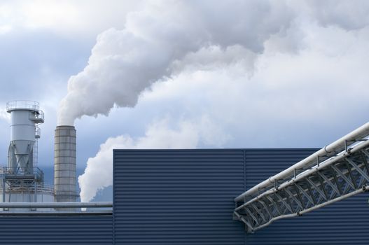 Detail of a modern industrial building with pipes, chimeys and smoke