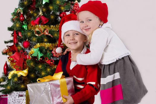 Little sister and brother hugging under Christmas tree