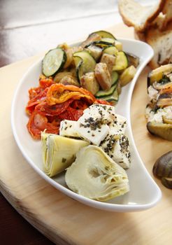 Delicious tray of rustic vegetables including artichokes, sundried tomatoes, zucchinis and feta cheese.