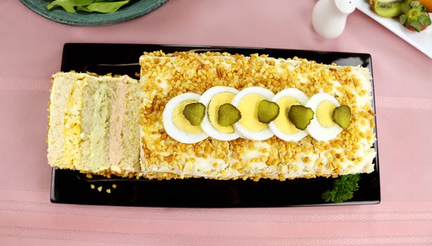 Layered salmon, avocado and curried egg loaf with a fruit platter and salad.