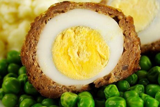 Delicious scotch egg with peas, carrots and mashed potato.