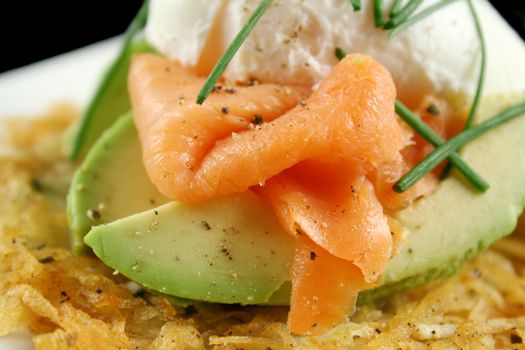 Beautiful salmon and poached egg stack on a hash brown with avocado.