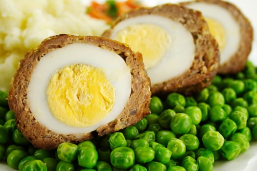 Delicious scotch eggs with peas, carrots and mashed potato.
