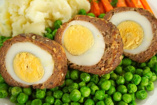 Delicious scotch eggs with peas, carrots and mashed potato.