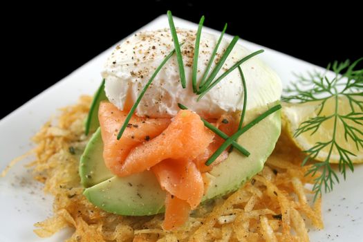 Beautiful salmon and poached egg stack on a hash brown with avocado.