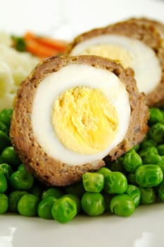 Delicious scotch eggs with peas, carrots and mashed potato.