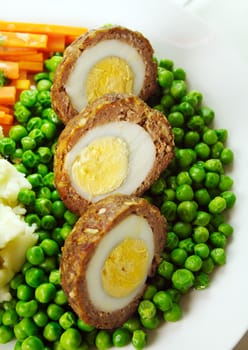 Delicious scotch eggs with peas, carrots and mashed potato.