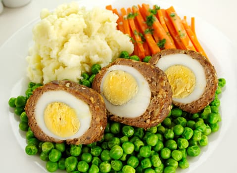 Delicious scotch eggs with peas, carrots and mashed potato.