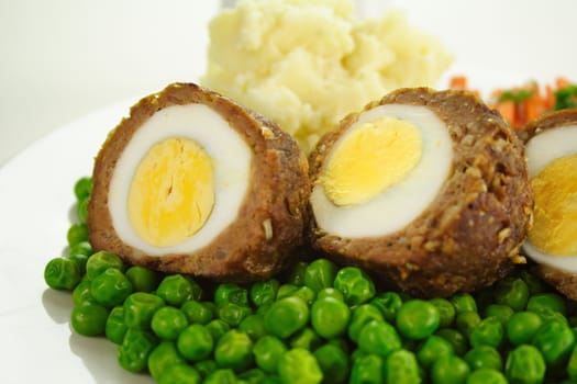 Delicious scotch eggs with peas, carrots and mashed potato.