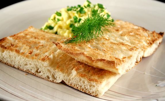 Scrambled eggs on turkish bread with shallots fennel and parsley.