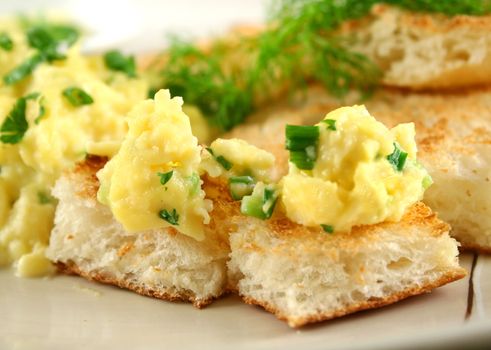 Scrambled eggs on turkish bread with shallots fennel and parsley.