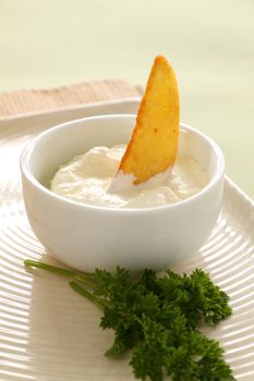 Crisp baked potato wedge in a bowl of sour cream.