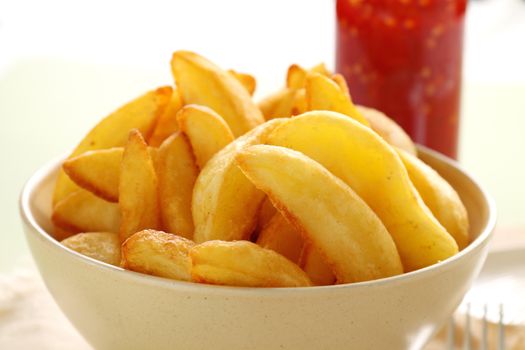 Bowl of freshly fried crisp potato wedges ready to serve.