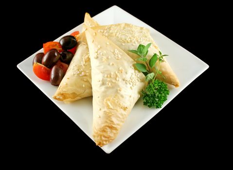 Spinach and feta cheese triangles with olives and cherry tomatoes.