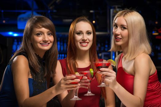 three girls raised their glasses in a nightclub, have fun with friends