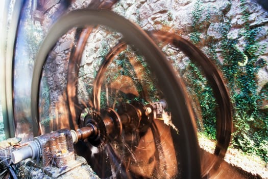 Working ancient millwheel at stone-wall mill building turning motion blurred by long exposure
