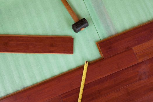 Home improvement construction laying stained brown wooden bamboo hardwood boards flooring and rubber mallet tool