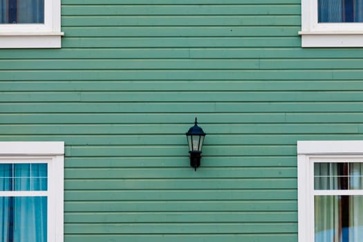 Green building facade with windows around centered exterior lamp as architecture background pattern abstract