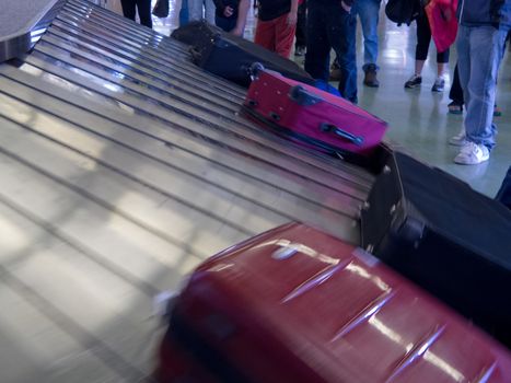 Airport baggage claim, passengers wait for their luggage on conveyor belt after flight landing