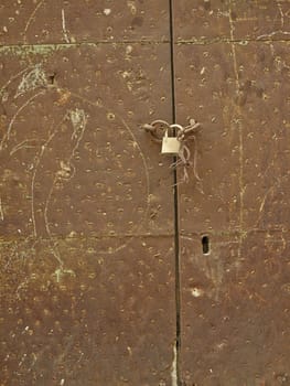Old rusty metal door with a padlock and keyhole and chalk drawings