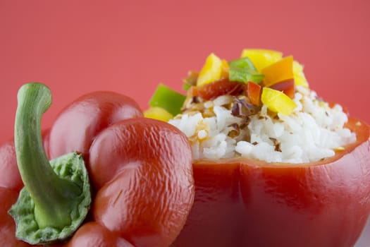 Stuffed red pepper in a dish on red background .